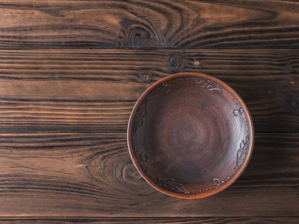 Clay bowl on a brown wooden table. Flat lay. - 写真・画像