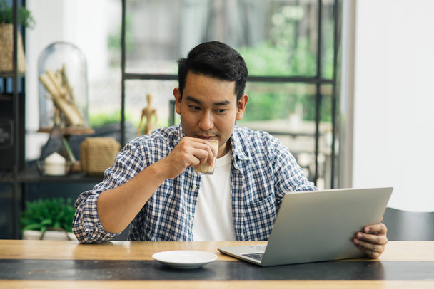 Hombre asiático inteligente que trabaja con el ordenador portátil en la cafetería, concepto de trabajo
. - Foto, Imagen