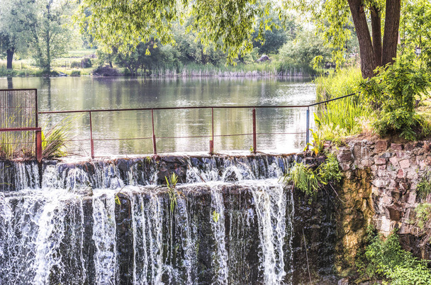 Blick auf ein Fragment eines Staudamms mit einem künstlichen Wasserfall, der infolge eines Seeunfalls in einem Waldgebiet der Kiewer Region, Ukraine, entstanden ist. - Foto, Bild