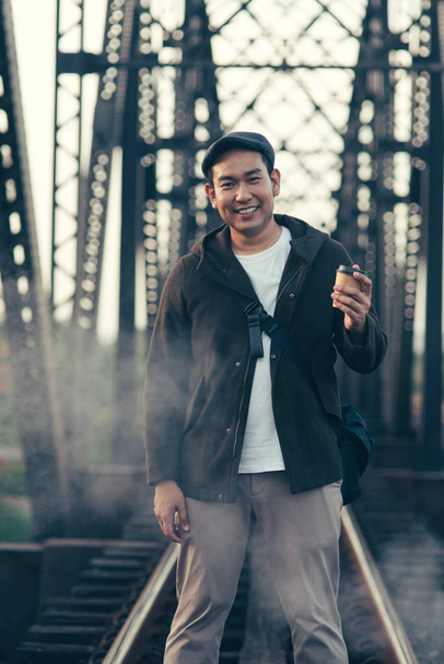 Asian tourist man in overcoat drinking takeaway coffee cup with  - Zdjęcie, obraz