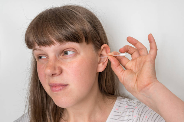 Mujer limpia sus orejas sucias con hisopo de algodón
 - Foto, imagen