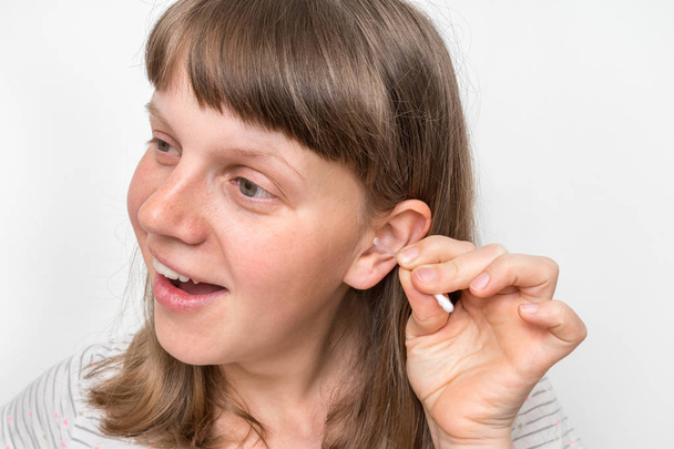 A nő vattapamaccsal tisztítja a mocskos fülét. - Fotó, kép