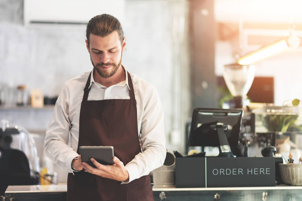Male barista holding and looking at digital tablet. - Foto, immagini