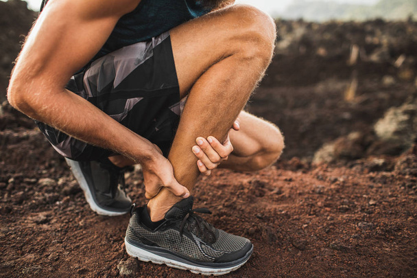Achilles injury on running outdoors. Man holding Achilles tendon - Φωτογραφία, εικόνα
