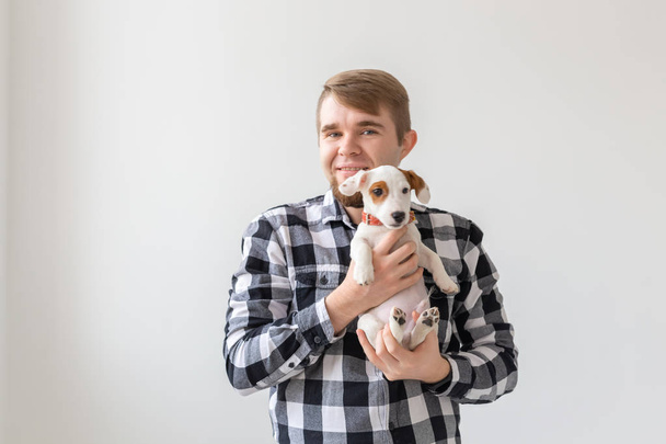 Kişi, evde beslenen hayvan ve köpek kavramı - beyaz arka plan holding köpek yavrusu Jack Russell Terrier gülümseyen adam - Fotoğraf, Görsel