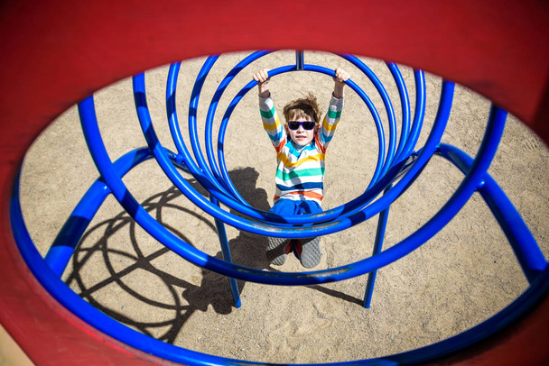 Schattig jong kind jongen of kind spelen in tunnel op speelplaats - Foto, afbeelding