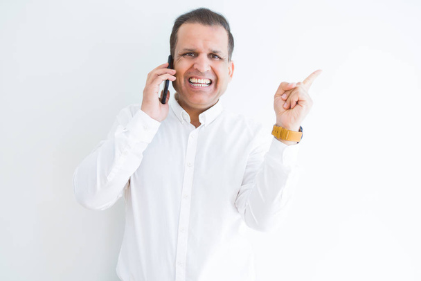 Middle age man calling using smartphone very happy pointing with hand and finger to the side - Foto, imagen