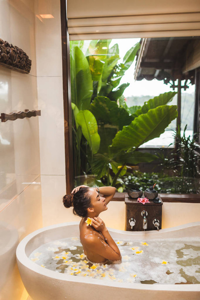 泡、泡とイエロと花風呂で楽しむアジアの女性 - 写真・画像