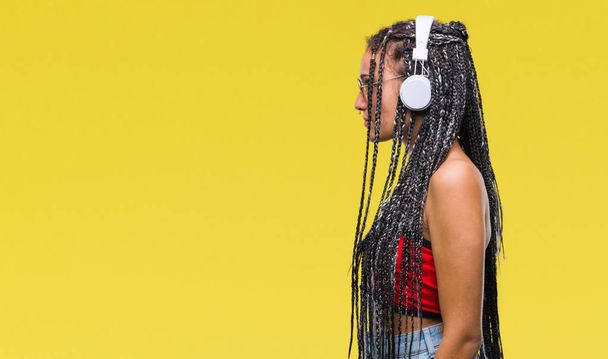 Young braided hair african american with birth mark wearing headphones over isolated background looking to side, relax profile pose with natural face with confident smile. - Fotografie, Obrázek