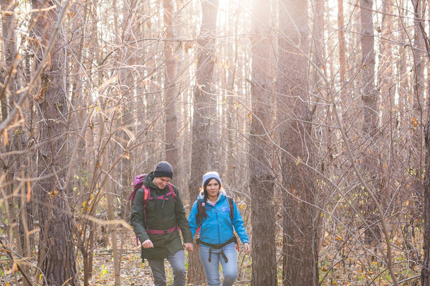 aventura, viajes, turismo, senderismo y concepto de personas - pareja sonriente caminando con mochilas sobre fondo natural de otoño
 - Foto, imagen