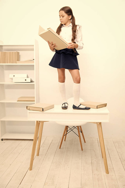 Schoolgirl stand table work archive folder. Cute little bookworm. Pupil studying history read archive document. Search for historical facts. Born to be detective. Schoolgirl find interesting document - 写真・画像
