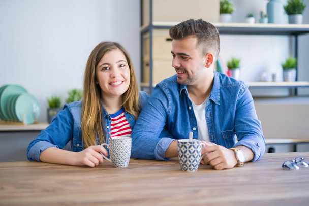 コーヒーを飲みながら休憩を取る若いカップルは、新しい家に引っ越すのに非常に幸せです - 写真・画像