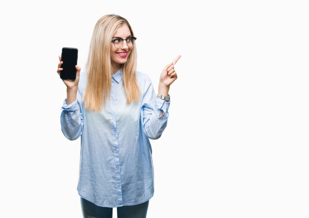 Genç güzel sarışın iş kadın gösteren ekran smartphone üzerinde izole arka tarafına el ve parmak ile işaret çok mutlu - Fotoğraf, Görsel
