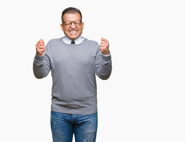 Middle age bussines arab man wearing glasses over isolated background excited for success with arms raised celebrating victory smiling. Winner concept. - Foto, Bild