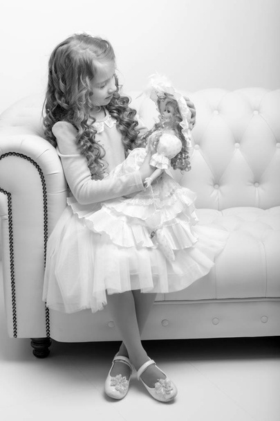 Cute little girl playing with a doll. - Φωτογραφία, εικόνα