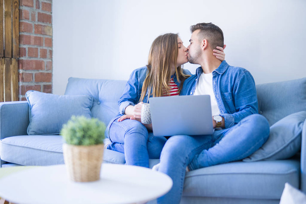 Young couple relaxing sitting on the sofa using the computer laptop - Photo, Image