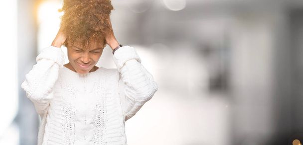 Çünkü çaresiz ve stresli baş ağrısı acı izole arka plan üzerinde kış kazak giyen güzel genç Afro-Amerikan kadın ağrı ve migren. Ellerini kafasına. - Fotoğraf, Görsel