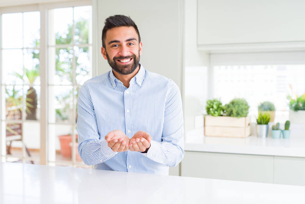 Handsome hispanic business man Smiling with hands palms together receiving or giving gesture. Hold and protection - Photo, Image