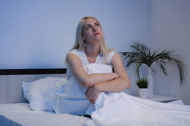 Mujer deprimida triste sentada en su cama tarde en la noche, ella es pluma
 - Foto, imagen