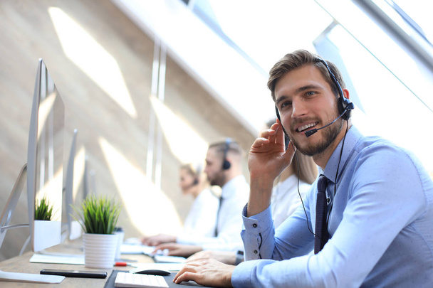 Portrait of call center worker accompanied by his team. Smiling customer support operator at work. - Foto, afbeelding