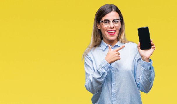 Молода красива бізнес-леді, показуючи порожній екран смартфона на ізольованому фоні дуже щасливий вказуючи рукою і пальцем
 - Фото, зображення