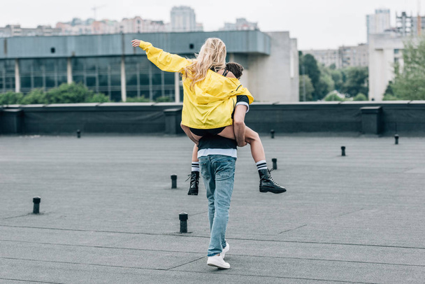 back view of woman in yellow jacket playing with man on roof  - Foto, immagini