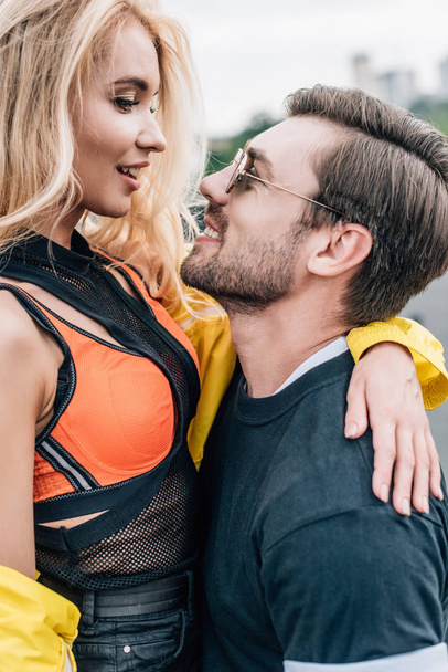 handsome man in glasses holding attractive woman on roof  - Foto, Bild