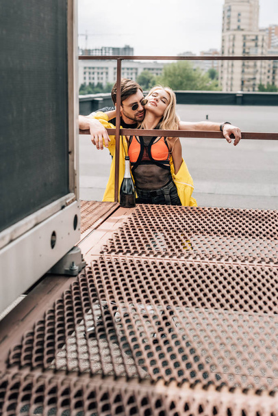 blonde woman and handsome man in glasses hugging on roof  - Photo, Image
