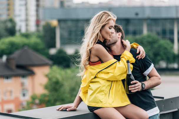 man holding bottle, kissing and hugging attractive woman  - Photo, Image