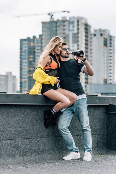 attractive woman sitting on roof and handsome man drinking champagne - Foto, immagini