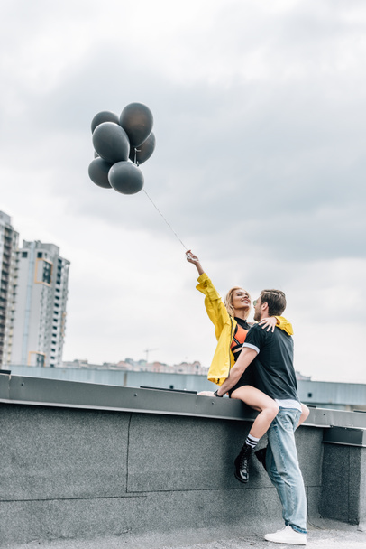 attractive woman holding black balloons and hugging with man  - Foto, Imagem