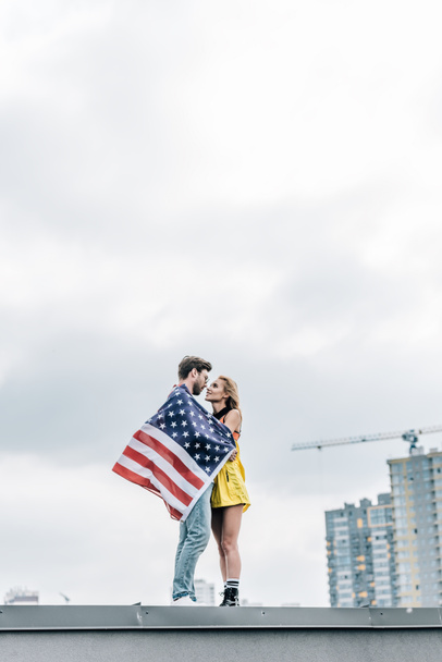 attrayant femme et bel homme avec drapeau américain étreignant sur le toit
  - Photo, image