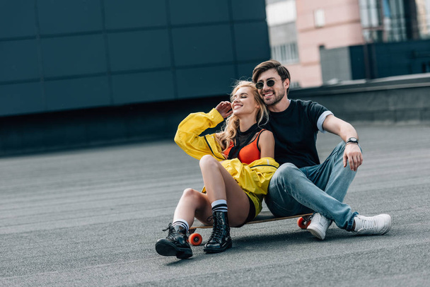 attractive woman and handsome man in glasses sitting on skateboard  - Valokuva, kuva