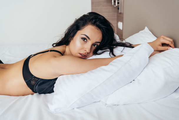 sensual brunette young woman in black bra lying on pillow - Photo, Image