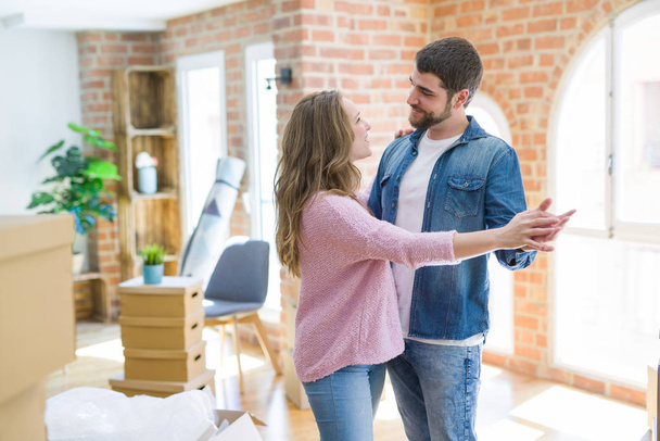 Young couple dancing celebrating moving to new apartment around cardboard boxes - Photo, image