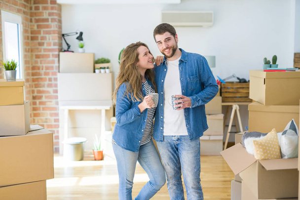 Jeune couple se détendant de déménager dans une nouvelle maison en buvant un café autour de boîtes en carton
 - Photo, image