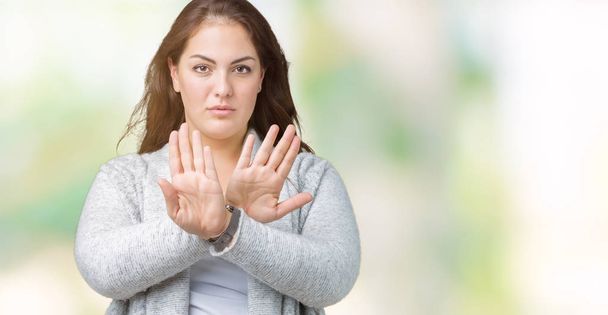 Beautiful plus size young woman wearing winter jacket over isolated background Rejection expression crossing arms and palms doing negative sign, angry face - Photo, Image