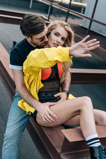 attractive and blonde woman showing hand and handsome man hugging her  - Foto, Imagem