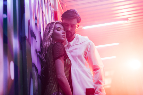 attraktive und blonde Frau umarmt einen hübschen Mann in einem Nachtclub - Foto, Bild