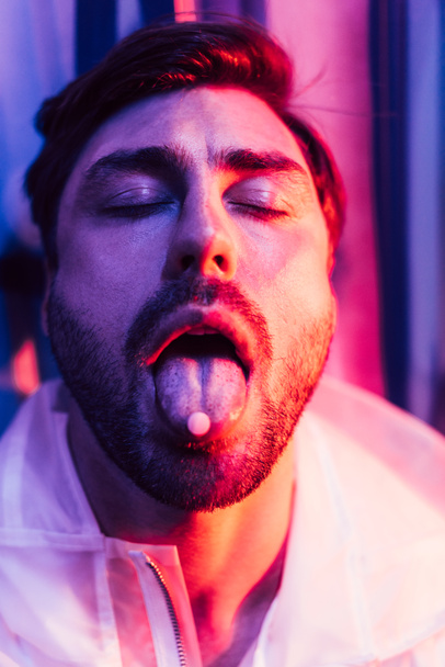 handsome man with closed eyes and LSD on tongue - Photo, Image