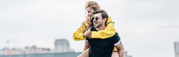 panoramic shot of attractive and blonde woman and handsome man hugging on roof  - Fotó, kép