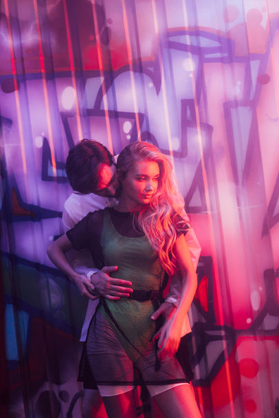 ελκυστική και ξανθιά γυναίκα Αγκαλιάζοντας με όμορφος άντρας στο νυχτερινό κέντρο - Φωτογραφία, εικόνα