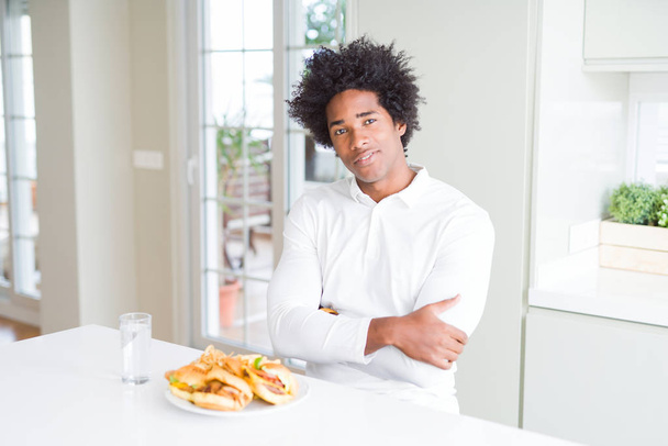 African American hungry man eating hamburger for lunch happy face smiling with crossed arms looking at the camera. Positive person. - Fotoğraf, Görsel