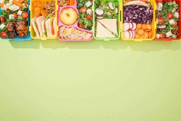top view of lunch boxes with food on green background - Photo, Image