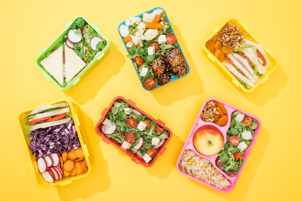 top view of lunch boxes with fresh food on yellow background - Photo, Image
