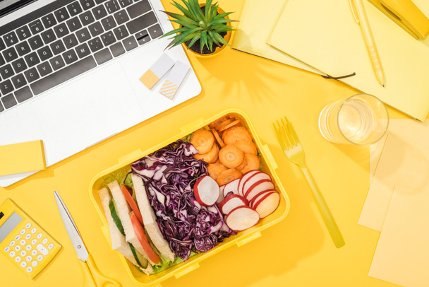 top view of delicious lunch in box at workplace with yellow background - Photo, Image