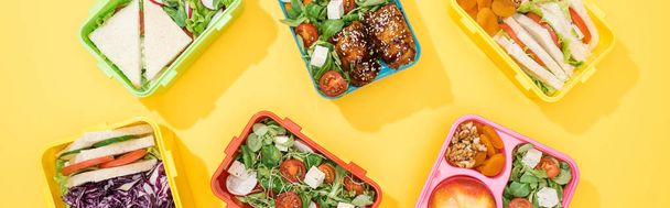 panoramic shot of lunch boxes with food on yellow background - Photo, Image
