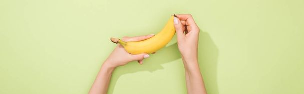 cropped view of woman holding banana in hands - Foto, afbeelding