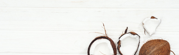 top view of coconut halves on white wooden surface, panoramic shot - Valokuva, kuva