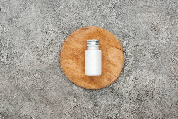 pohled na produkt z kokosových krás v láhvi na dřevěné desce na šedé, texturované pozadí - Fotografie, Obrázek